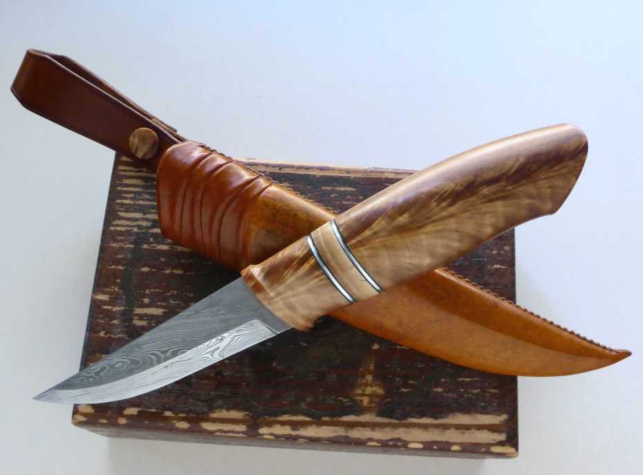 Blade in Damasteel, grinded by Robert Mattsson, handle in stabilized birchfork, mammoth and pewter spacer. Rawhide leather in the sheath. 